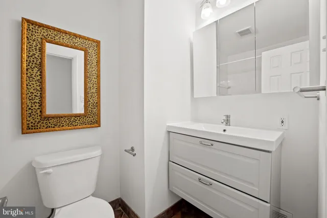 a bathroom with a toilet sink vanity and mirror