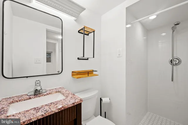 a bathroom with a granite countertop sink a toilet and mirror