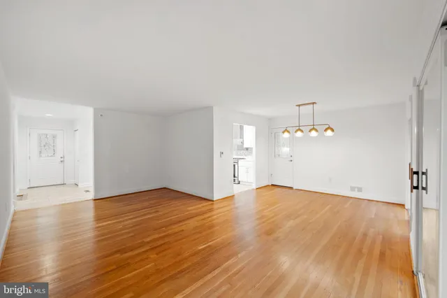 an empty room with wooden floor and chandelier