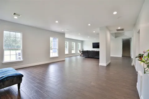 a view of an empty room with kitchen and window
