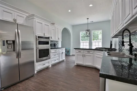 a kitchen with stainless steel appliances kitchen island granite countertop a stove a sink and a refrigerator