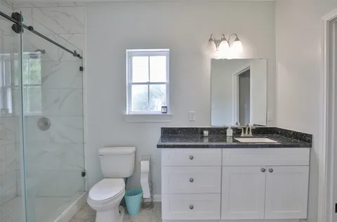 a bathroom with a granite countertop toilet sink and mirror