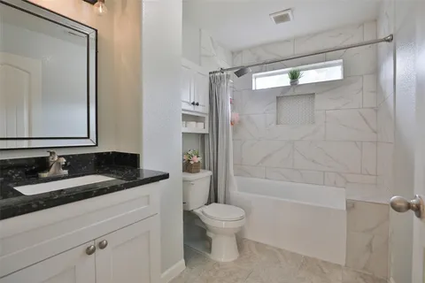 a bathroom with a granite countertop sink toilet a mirror and shower