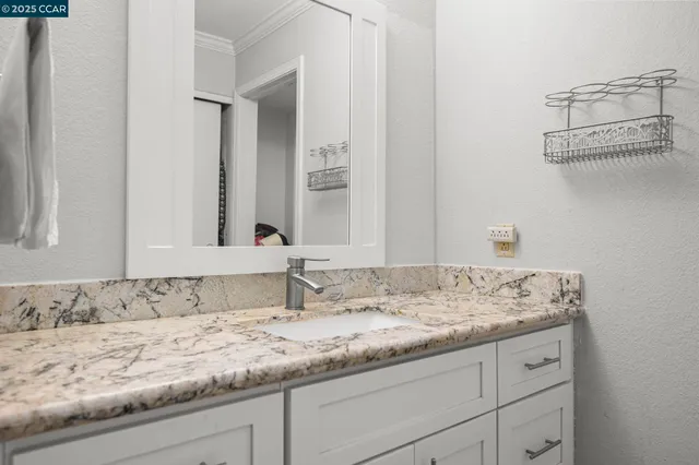 a bathroom with a granite countertop sink and a mirror