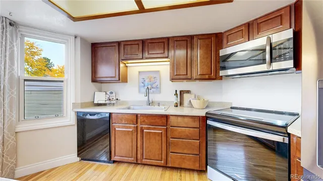 a kitchen with stainless steel appliances granite countertop a sink cabinets wooden floor and a window