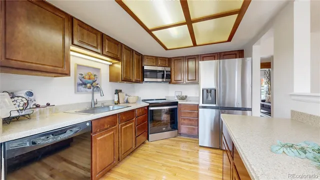 a kitchen with stainless steel appliances granite countertop a sink a stove top oven a refrigerator a sink with island and chairs