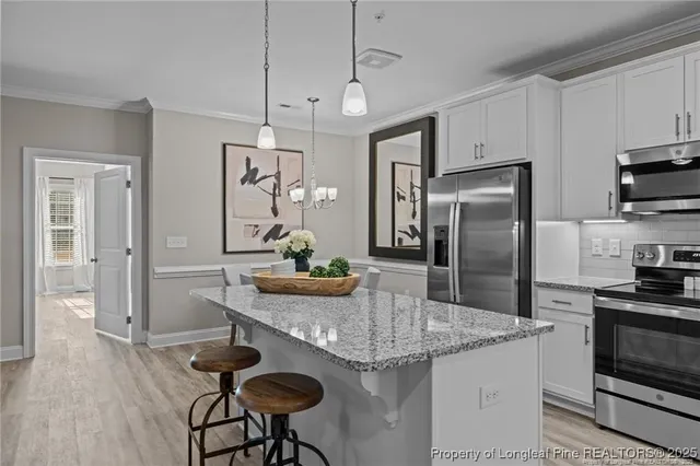 a kitchen with stainless steel appliances granite countertop a sink a stove a refrigerator cabinets and dining table