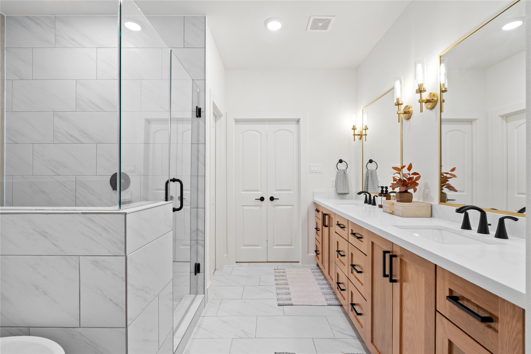 1614 Ojeman Road, Unit I Houston, TX 77055 - Photo 36 of 49 This beautifully designed primary bath showcases a large walk-in shower, quartz-topped dual vanities, custom wood cabinetry, and designer lighting that blends matte-black and gold accents for a refined, upscale feel.
