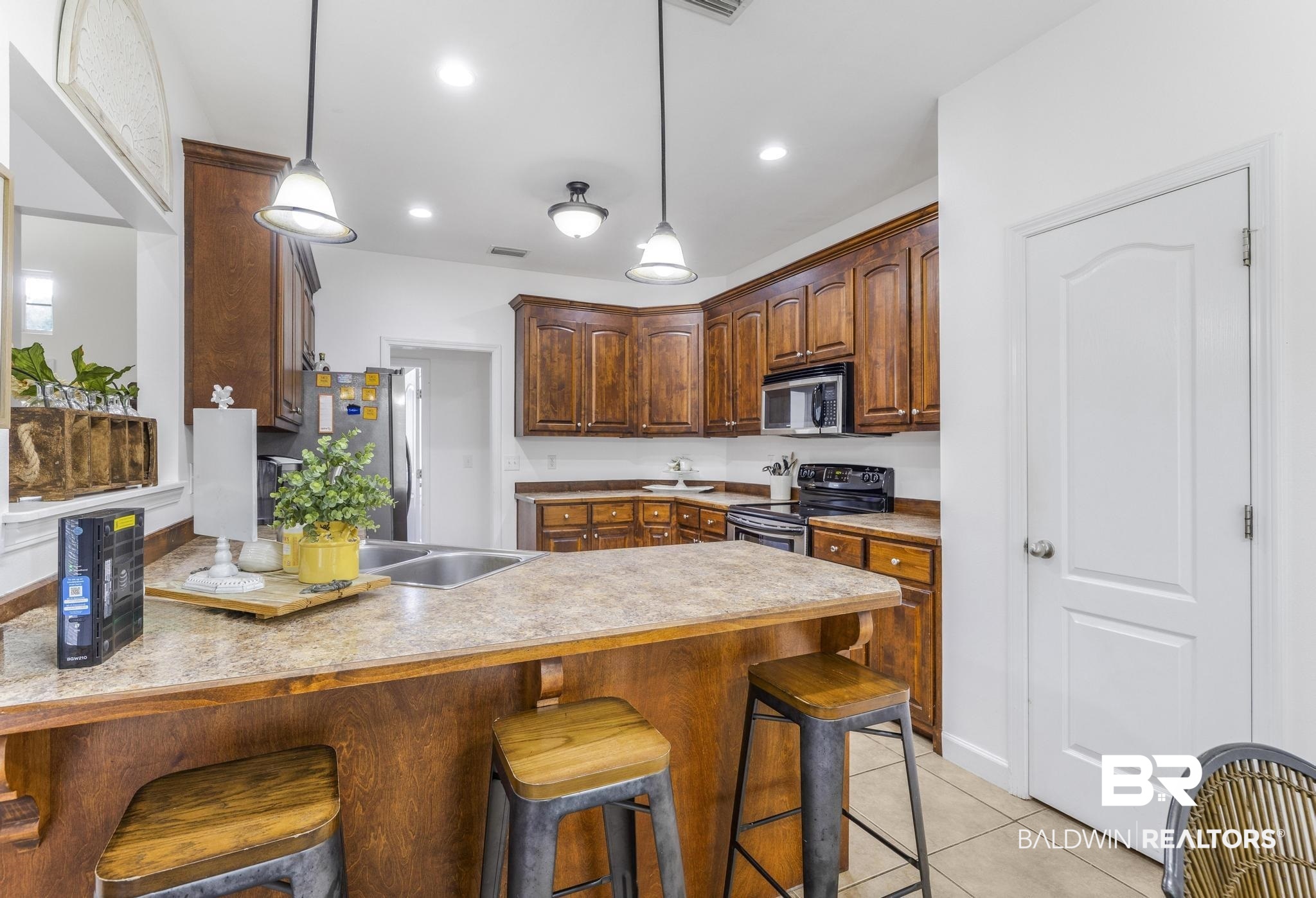 35814 Delvan Lane Bay Minette, AL 36507 - Photo 23 of 53 Kitchen featuring wood cabinetry, a double basin sink, and a peninsula with seating