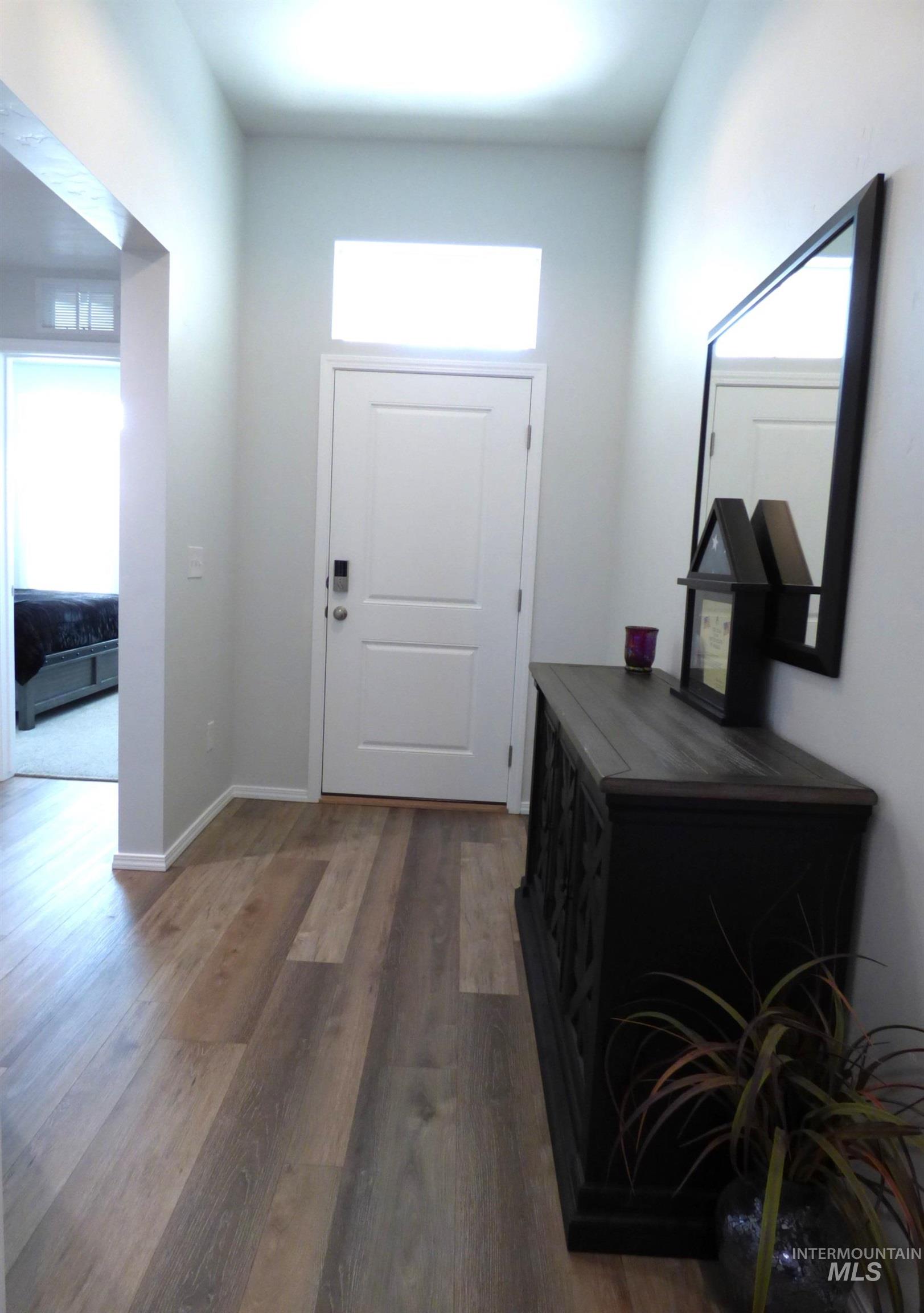2708 East Buckaroo Drive Kuna, ID 83634 - Photo 30 of 48 Entryway featuring wood-finish flooring, a white paneled door with a transom window, and a recessed archway