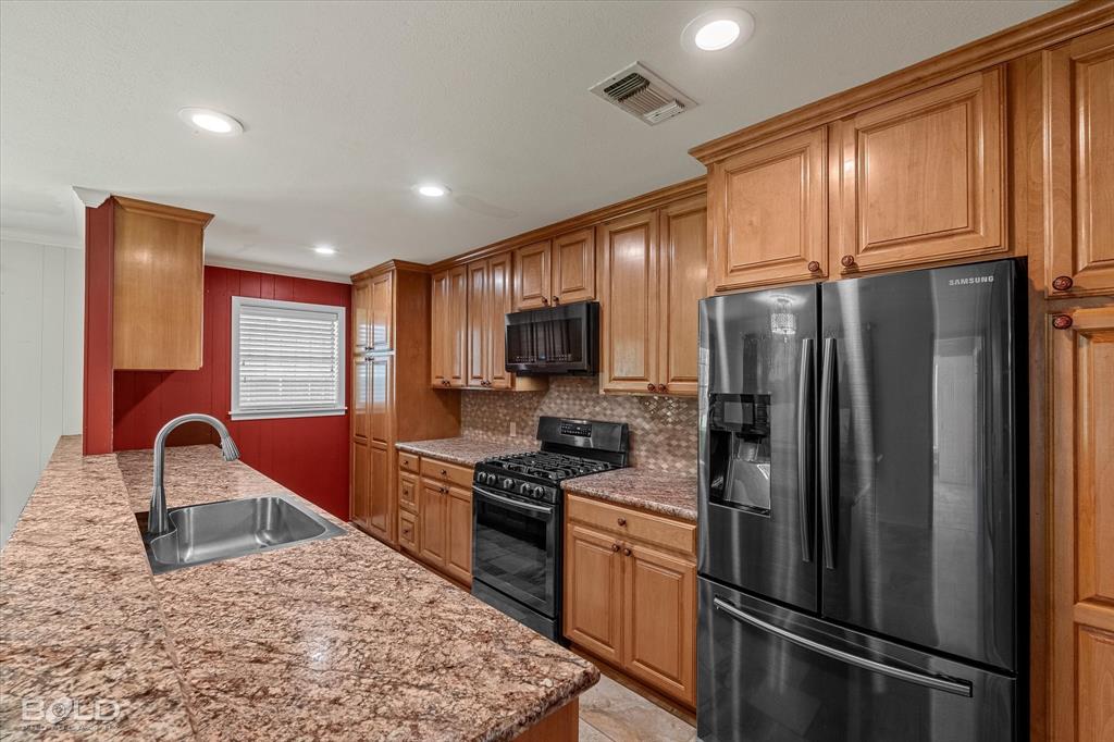 225 Marie Road Ringgold, LA 71068 - Photo 26 of 40 Kitchen featuring wood cabinetry, granite countertops, stainless steel sink with gooseneck faucet, black range, and black refrigerator