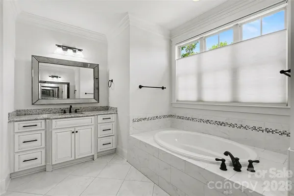 a spacious bathroom with a granite countertop sink mirror and bathtub