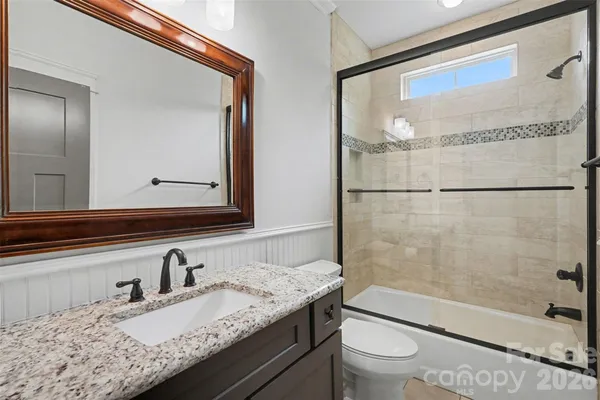 a bathroom with a granite countertop sink mirror vanity and toilet