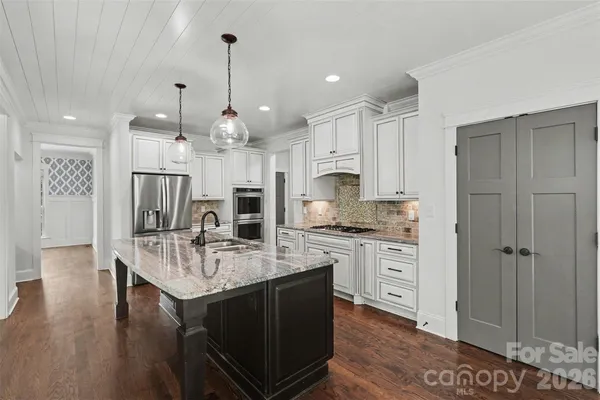 a kitchen with kitchen island granite countertop a sink cabinets and wooden floor