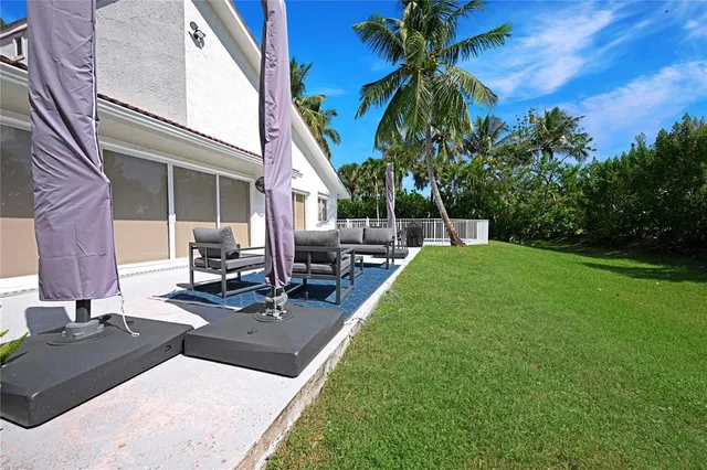a view of a patio with table and chairs potted plants and palm tree