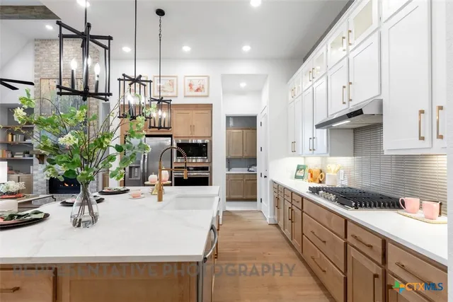 a kitchen with stainless steel appliances kitchen island granite countertop a sink a counter space and cabinets