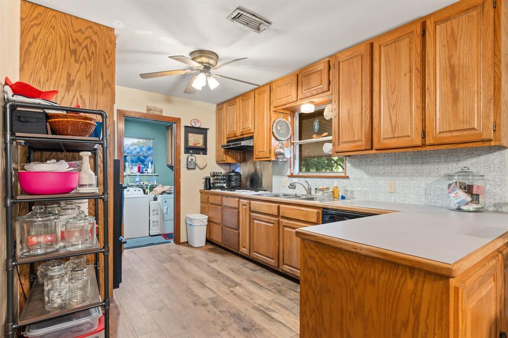 802 North Brazos Street Whitney, TX 76692 - Photo 10 of 33 a kitchen that has a lot of cabinets a sink and a stove with wooden floor