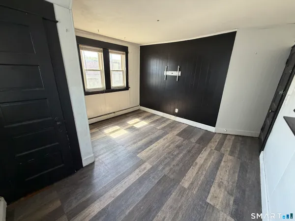 a view of an empty room with wooden floor and a window