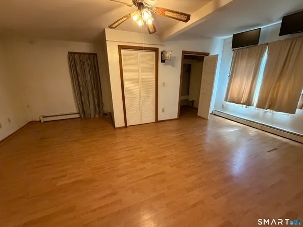 a view of an empty room with wooden floor and a window