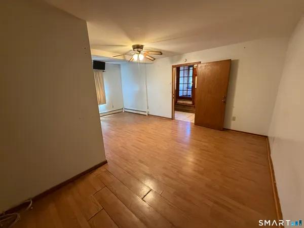 an empty room with wooden floor and chandelier fan