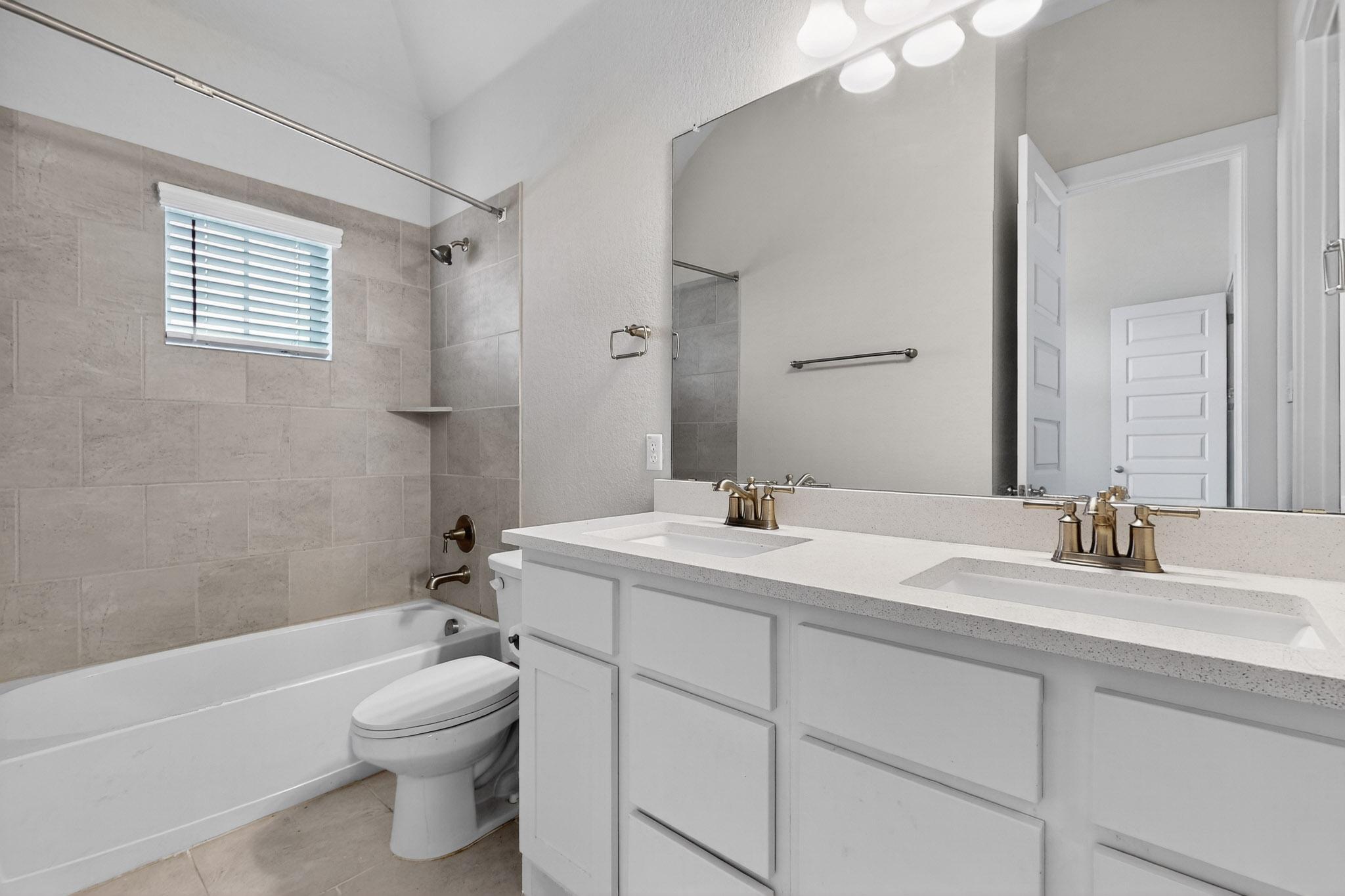 20912 Carries Ranch Road Pflugerville, TX 78660 - Photo 13 of 20 Tiled walls and a double vanity define this well-appointed bathroom space.