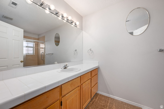 39 North Valley View Drive, Unit 51 St. George, UT 84770 - Photo 19 of 25 Bathroom vanity featuring a single sink, light wood cabinetry, and a white tile countertop