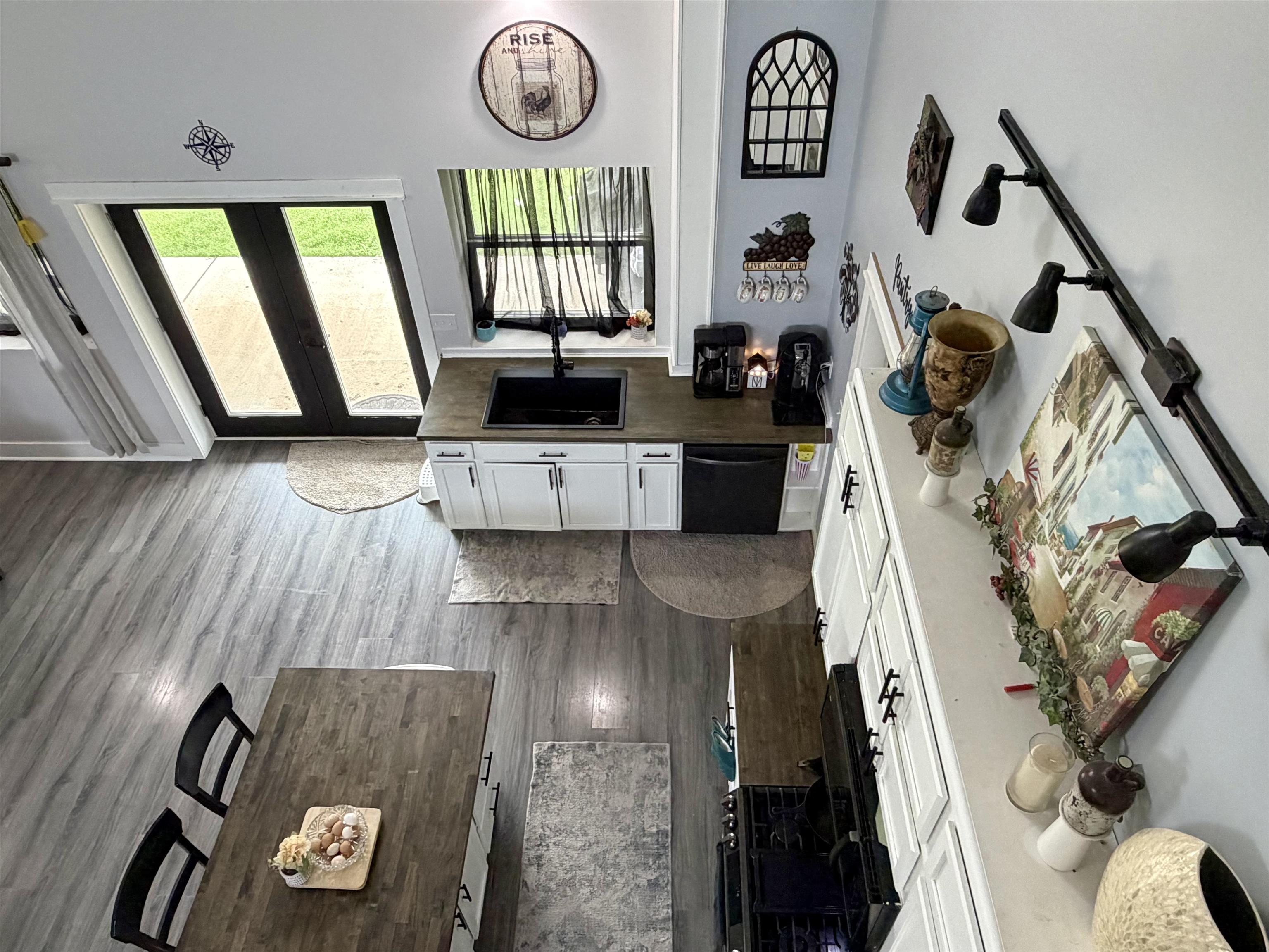 3670 Peavine Road Middleton, TN 38052 - Photo 33 of 36 Open-concept kitchen featuring wood-finish flooring, white cabinetry with dark hardware, a dark composite sink, and a black dishwasher
