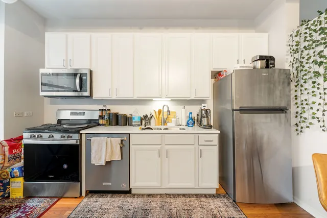 a kitchen with stainless steel appliances granite countertop a refrigerator stove and white cabinets