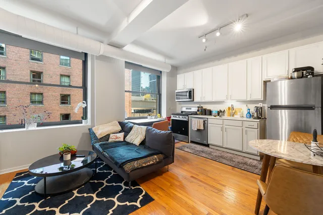 a kitchen with a stove a sink dishwasher a dining table and chairs with wooden floor