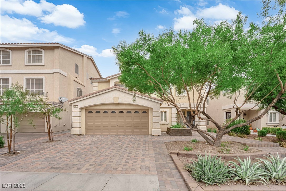 Beautifully maintained front elevation with mature trees, paver driveway, and great curb appeal.