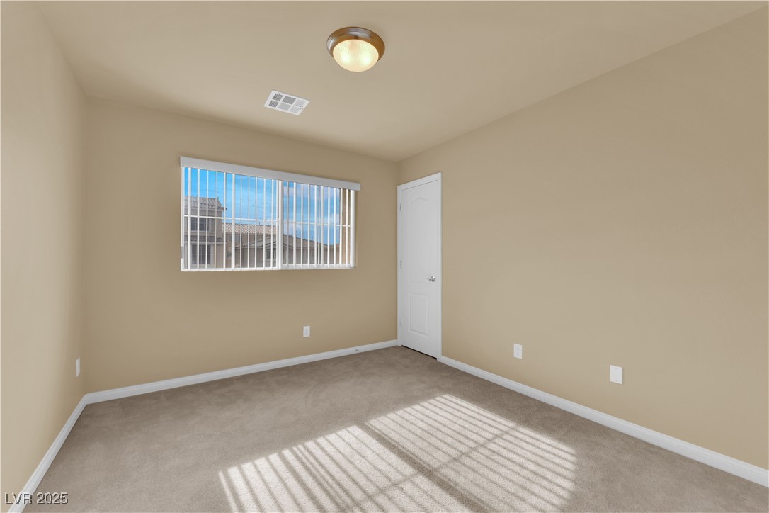 1142 Sax Fifth Avenue Henderson, NV 89052 - Photo 26 of 44 Light-filled guest bedroom with large window and plush carpet.