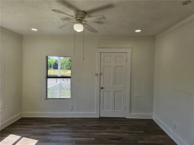 an empty room with wooden floor fan and windows