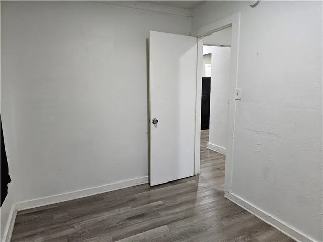 a view of an empty room with wooden floor and a mirror