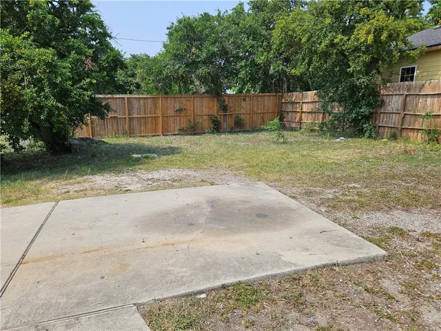 a view of a backyard with a tree and wooden fence