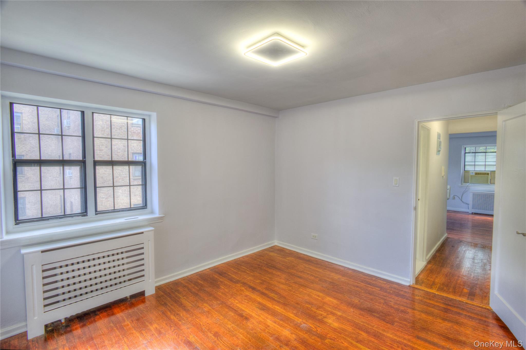 14401 78th Road, Unit 2B Queens, NY 11367 - Photo 17 of 29 Unfurnished room with radiator heating unit and dark wood-style floors
