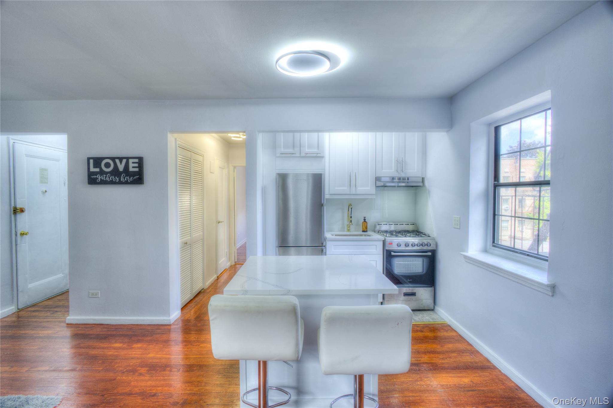 14401 78th Road, Unit 2B Queens, NY 11367 - Photo 5 of 29 Kitchen featuring white cabinets, stainless steel appliances, a breakfast bar area, dark wood-style flooring, and light stone countertops