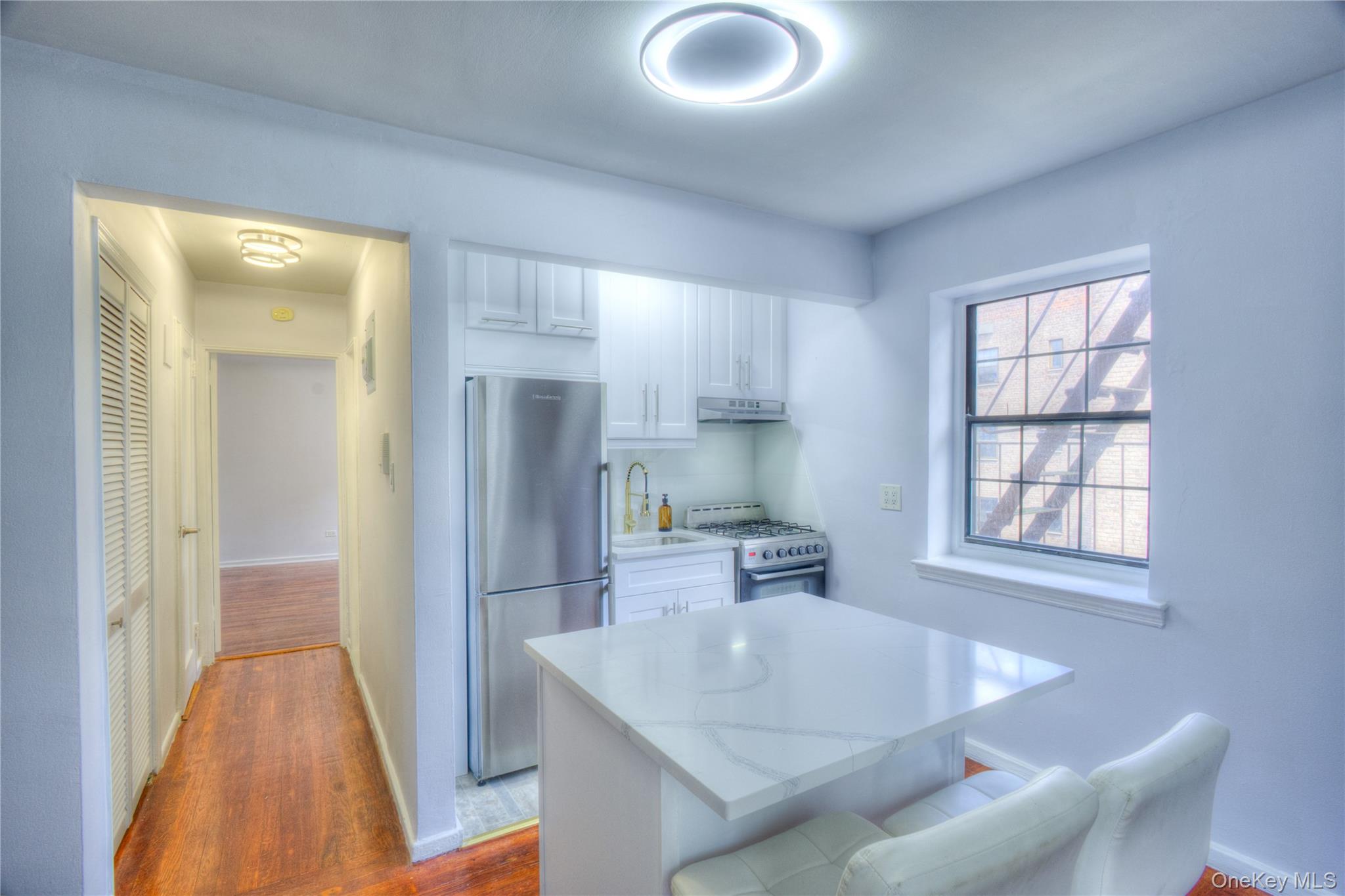 14401 78th Road, Unit 2B Queens, NY 11367 - Photo 6 of 29 Kitchen featuring white cabinets, dark wood-style floors, freestanding refrigerator, a breakfast bar area, and white gas range