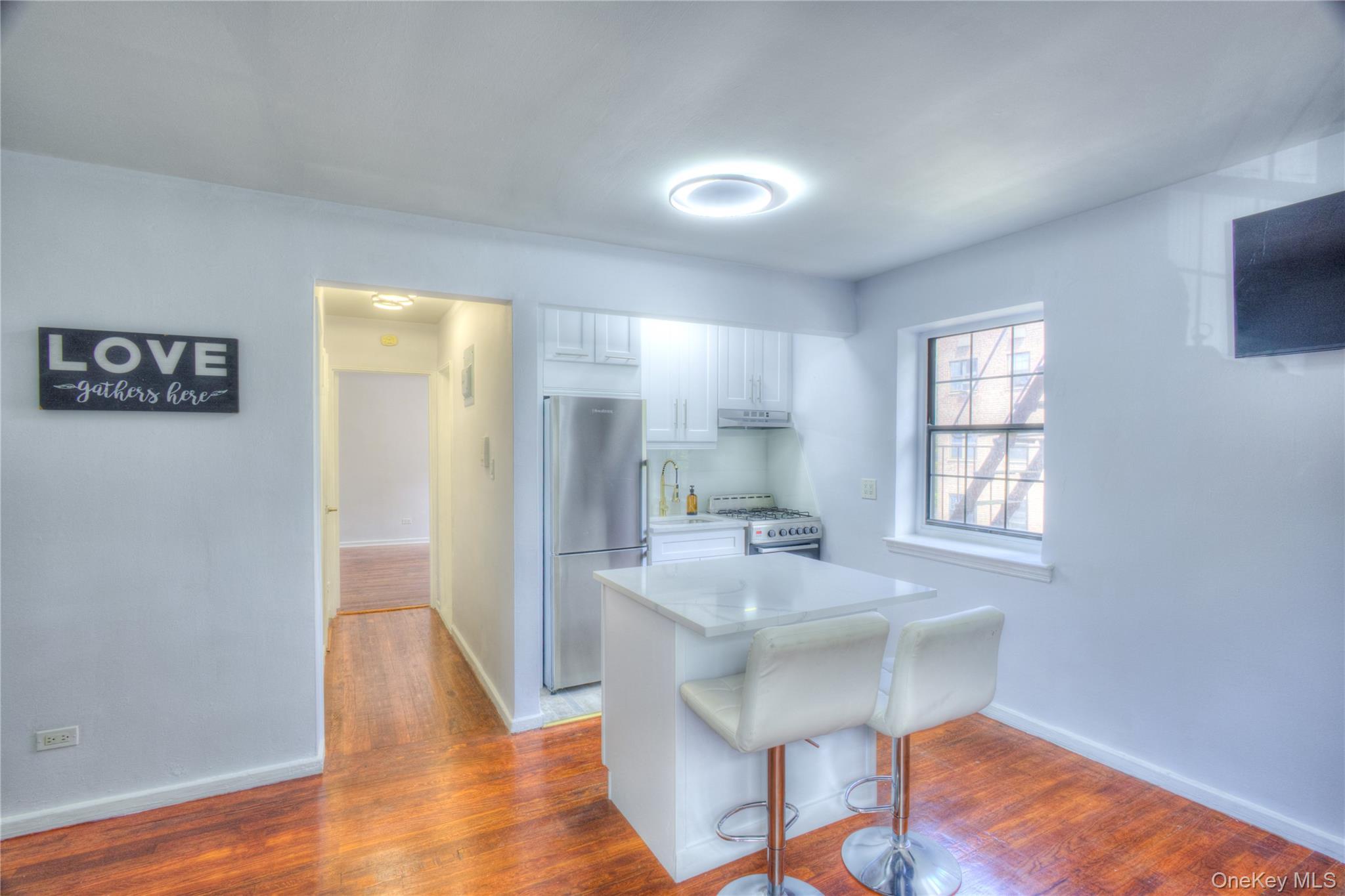 14401 78th Road, Unit 2B Queens, NY 11367 - Photo 7 of 29 Kitchen featuring freestanding refrigerator, dark wood-style flooring, a breakfast bar area, white cabinets, and white gas stove