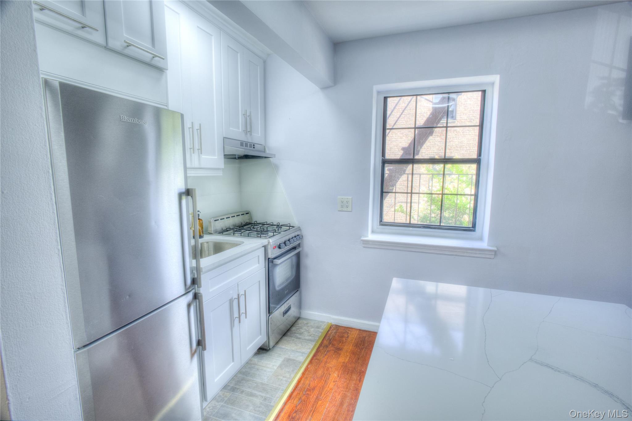14401 78th Road, Unit 2B Queens, NY 11367 - Photo 8 of 29 Kitchen featuring stainless steel appliances, white cabinetry, light wood-style flooring, and under cabinet range hood