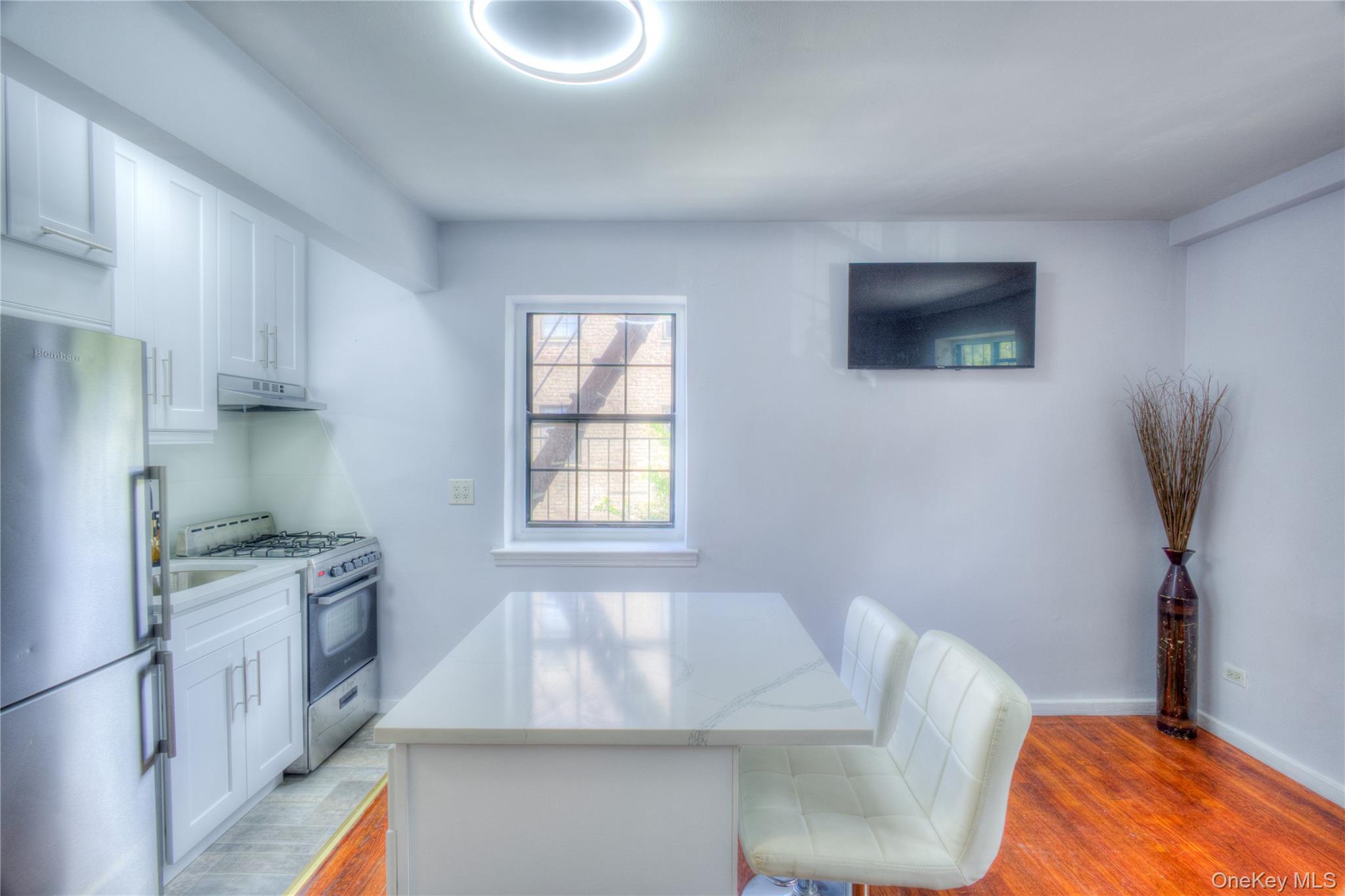 14401 78th Road, Unit 2B Queens, NY 11367 - Photo 9 of 29 Kitchen with light wood-style floors, freestanding refrigerator, stainless steel gas range oven, and white cabinetry