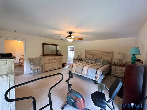 a spacious bedroom with a bed a couch and a flat tv screen on the dresser