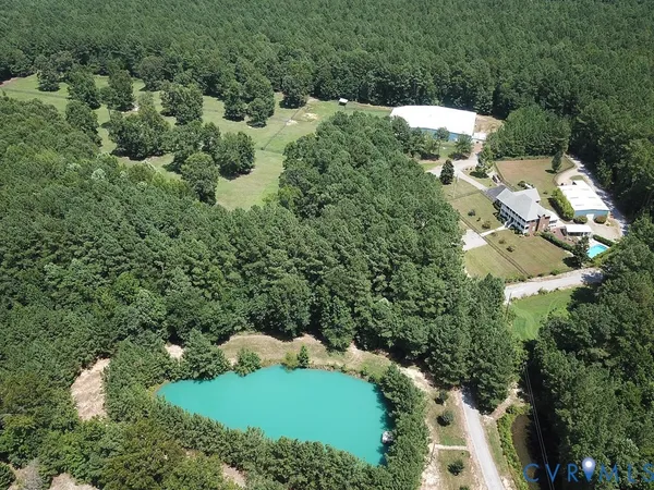 an aerial view of residential house with outdoor space and trees all around