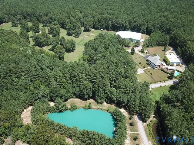 an aerial view of residential house with outdoor space and trees all around