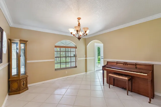 a dining room with chandelier fan and kitchen view