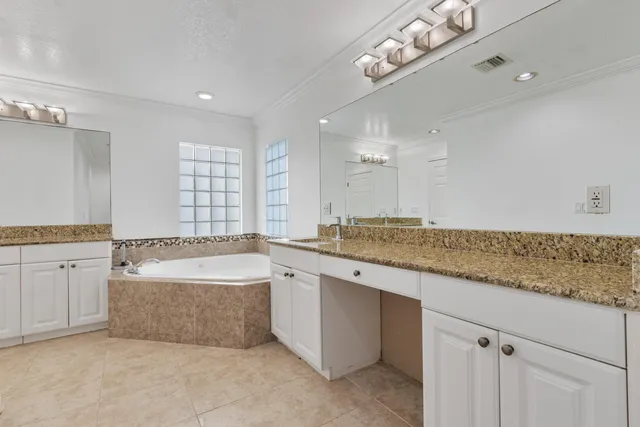 a bathroom with a granite countertop tub sink and mirror