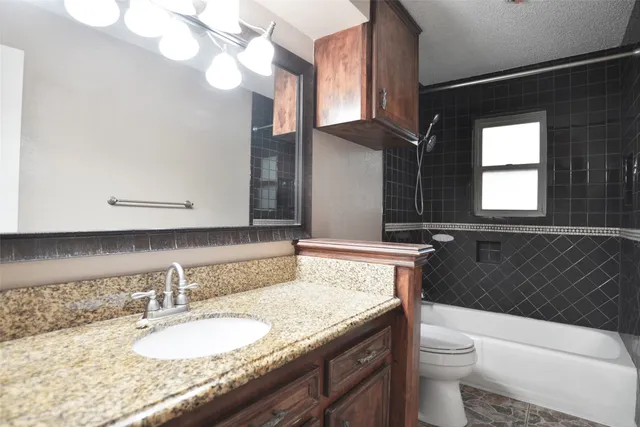a bathroom with a granite countertop sink a toilet and a mirror