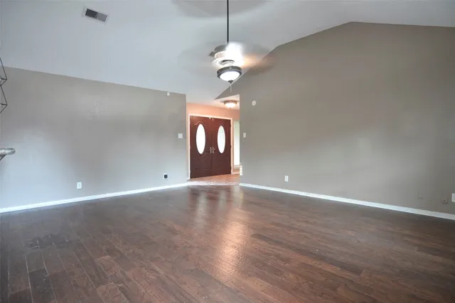 a view of an empty room with a window and wooden floor