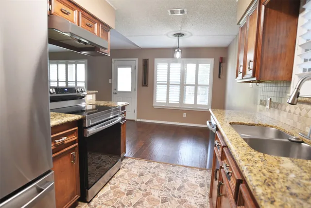 a kitchen with stainless steel appliances granite countertop a sink stove and cabinets