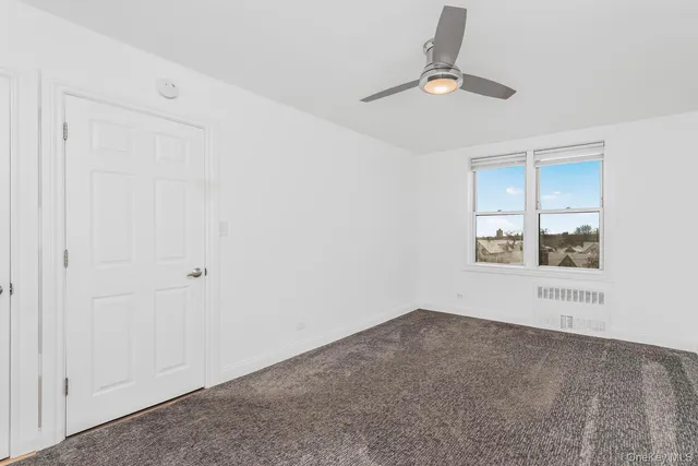 an empty room with a window and ceiling fan