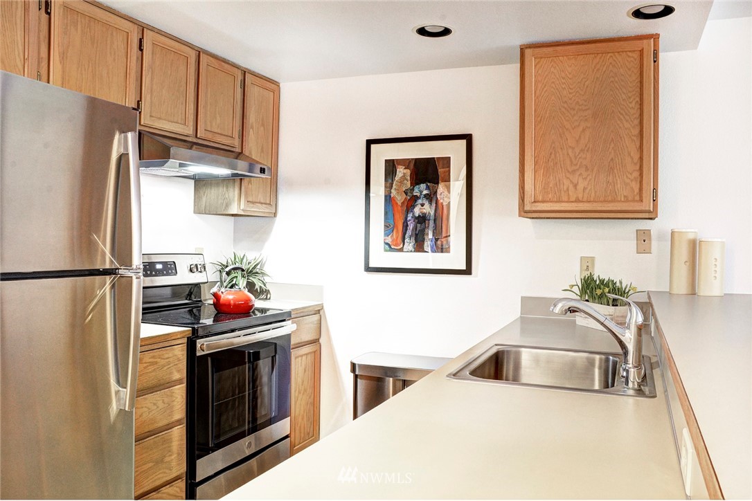 3901 Fremont Avenue North, Unit 206 Seattle, WA 98103 - Photo 5 of 15 a kitchen with stainless steel appliances a refrigerator a sink a stove and white cabinets